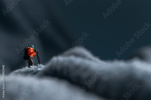 A miniature mountain climber figurine on a fuzzy fleece lining resembling a snow-covered surface, with a blurred background of a mountain or ice wall
