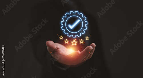 Businessman hand holding glowing gear with check mark and five stars symbolizing quality assurance customer satisfaction service excellence and professional business success on dark background