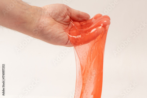 Red slime toy in man hand isolated on white.