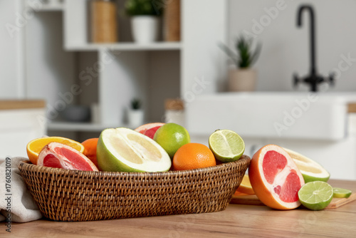 Basket with tasty citrus fruits on table in kitchen, closeup