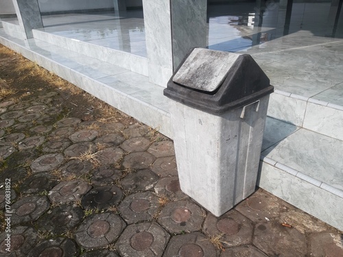Outdoor Trash Bin beside Building Entrance on Sunny Day