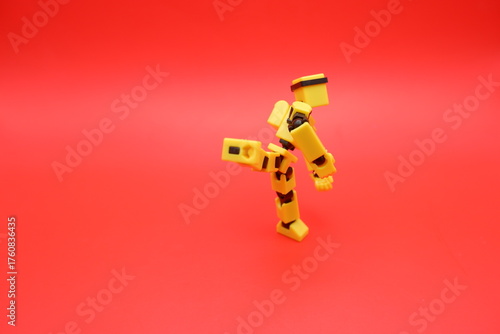 Yellow Dummy Action Figure Performing a Kick Pose on Red Background