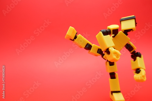 Yellow Dummy Action Figure Performing a Kick Pose on Red Background