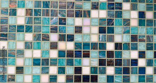 Decorative wall of glass mosaic tiles in shades of blue, teal, and white with reflective texture.