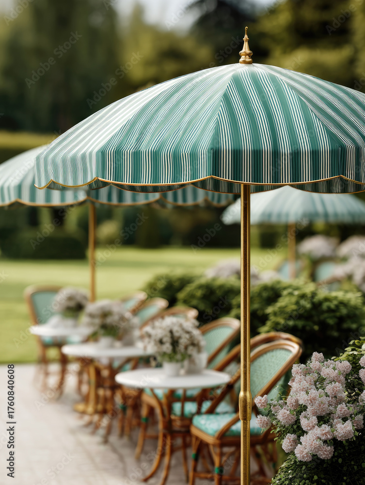 Obraz premium Vintage green and white striped umbrella shades outdoor cafe tables with floral arrangements, creating charming and inviting garden setting