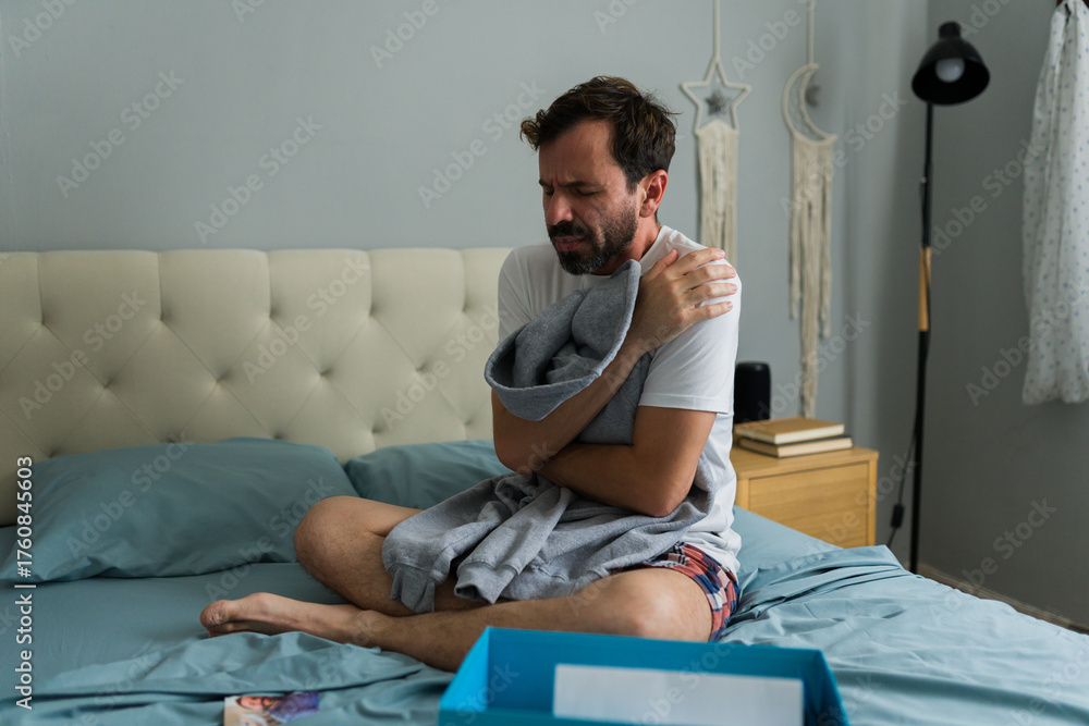 Obraz premium Depressed man sitting on bed hugging ex-girlfriend sweatshirt after breakup