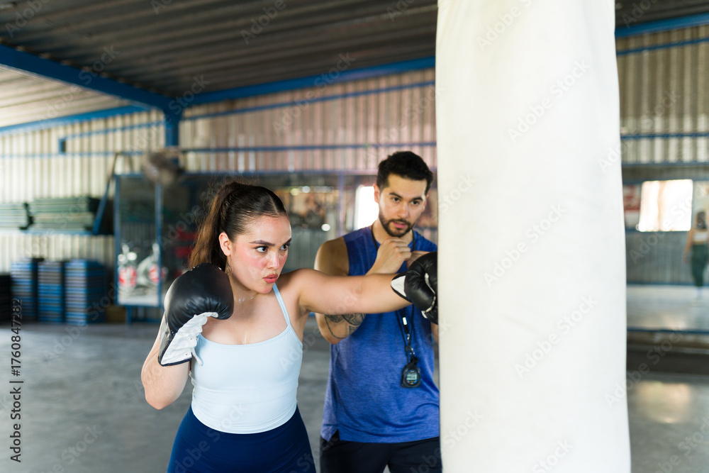 Obraz premium Woman training boxing punch with personal coach