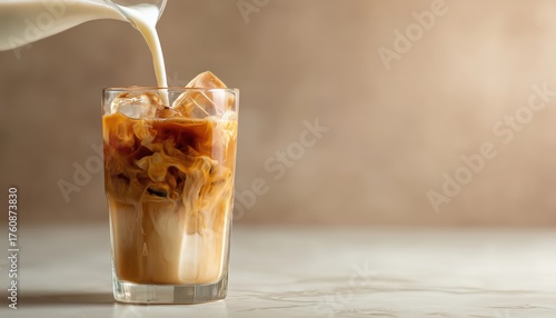 Creating A Refreshing Iced Latte: Pouring Milk Into Coffee With Ice Cube On Contemporary Beige Background In Vertical Format. Vietnamese Iced Coffee Still Life.