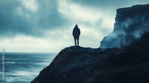 A lone figure stands on the edge of a cliff, gazing out at the vast ocean under a moody sky