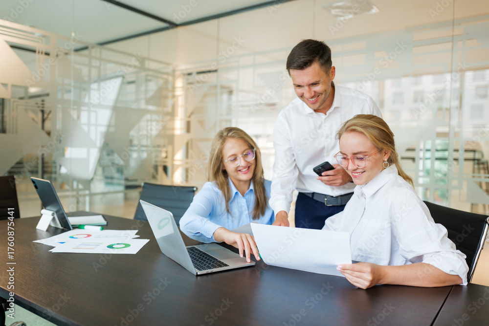 Fototapeta premium Team members collaborating in a modern office space while reviewing project documents and discussing ideas