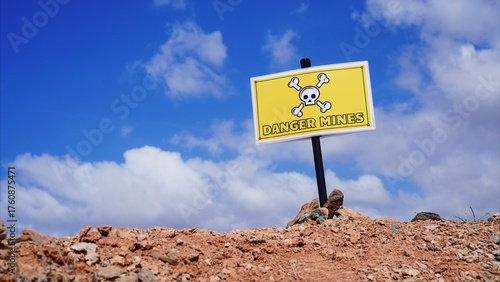 Yellow hazard sign with a skull and crossbones warning of danger mines, representing a critical issue of unexploded ordnance in post conflict zones and international collaboration for land clearance