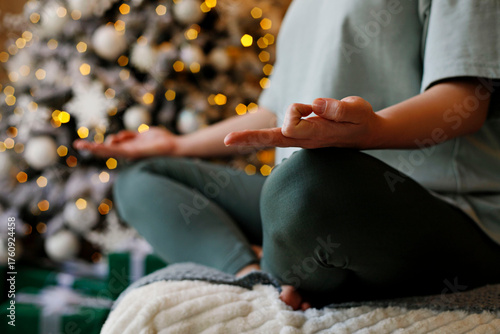 Individual practicing mindfulness meditation in a cozy indoor setting, surrounded by festive decorations and soft lighting, promoting relaxation and inner peace during the holiday season