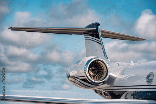 Konstfotografi Close-up of a modern business jet tail and turbofan engine showing aerodynamic design and high-bypass fan blades under partly cloudy skies