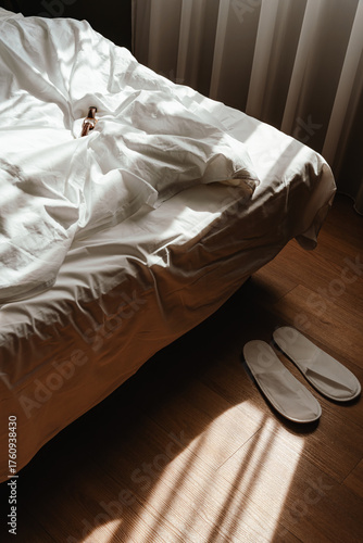Morning Light On Unmade Bed And White Slippers