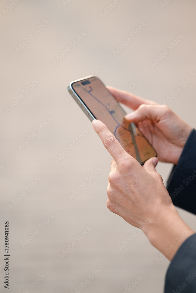 Fototapeta premium Vertical close-up of female hands holding smartphone with navigation map on screen. Concept of gps navigation, travel route, and mobile technology.