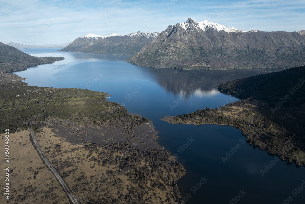 Fototapeta premium Aerial View of a Deep Blue Lake Surrounded by Forest and Snow-Capped Mountains