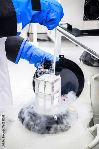 Close-up scientist handling sperm freezing tank storage with liquid nitrogen in laboratory