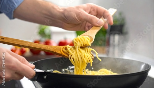 Fototapeta Naklejka Na Ścianę i Meble -  Cooking Spaghetti - Stirring Noodles in a Pan with Wooden Utensils.