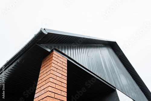 Bild auf Leinwand contractor examining brick and metal details, inspecting gabled roof with brick