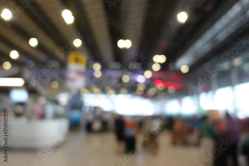Blurred view of passengers and people at  International Airport. Travelers walking and checking flight information boards in the terminal. Busy atmosphere of people with luggage, lights, and airport.
