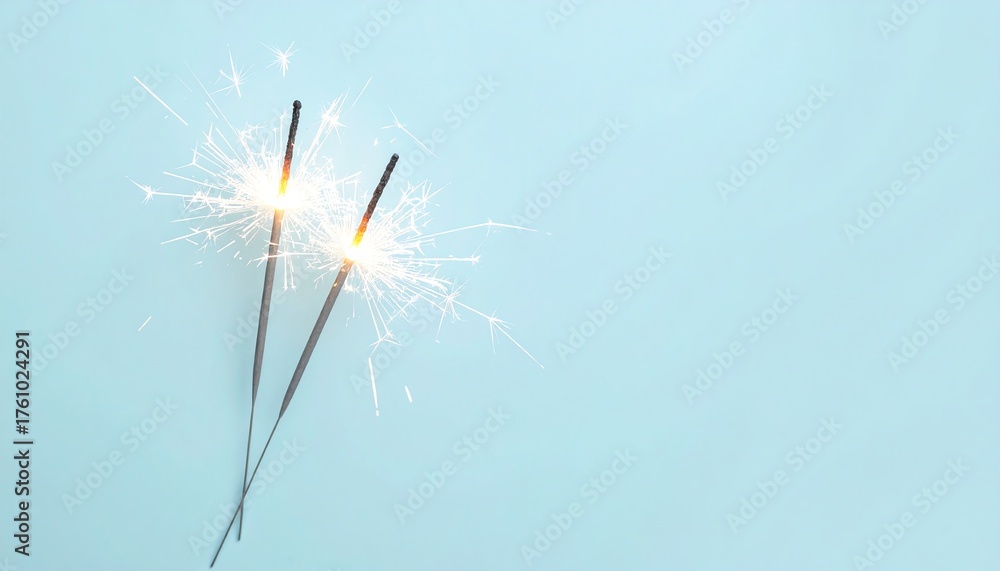 Naklejka premium Single sparkler glowing brightly against a light blue background creating a festive atmosphere
