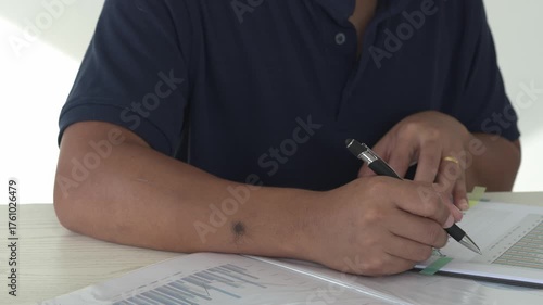 Focused young asian man reading and checking paper documents, signing the contract to send to her business partner. Concentrated smart ambitious businessman is organizing the paper works.