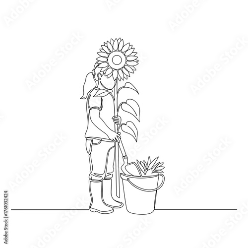Young girl gardening with giant sunflower and shovel by flower pot