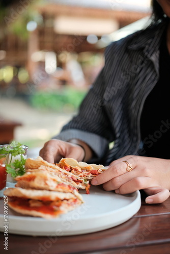 Woman enjoying a delicious quesadilla with fresh herbs and a vibrant sauce for lunch, perfect for a healthy and tasty midday meal inspiration