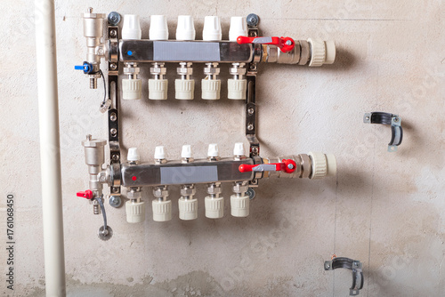 Modern plumbing distribution manifold installed on a concrete wall in a residential building's utility area