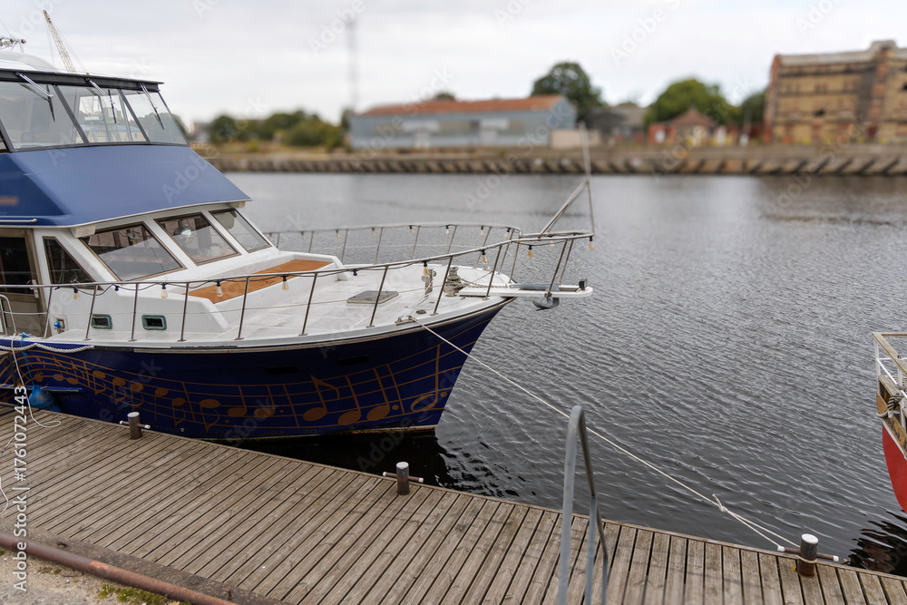 Fototapeta premium Blue and White Motor Yacht Moored at Wooden Dock