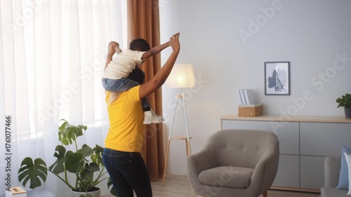 A loving mother carries her young son on her shoulders as they play together in a bright and spacious living room. The atmosphere radiates warmth and affection.