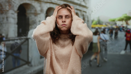 Photography Woman outside roman coliseum looking stressed in busy city street wearing sweater on a bright day