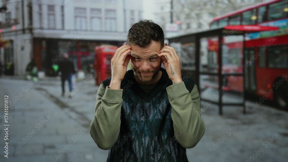 Fototapeta premium Man showing various emotions on urban street with double-decker bus and british phone booth nearby, conveying frustration and contemplation in a city setting.