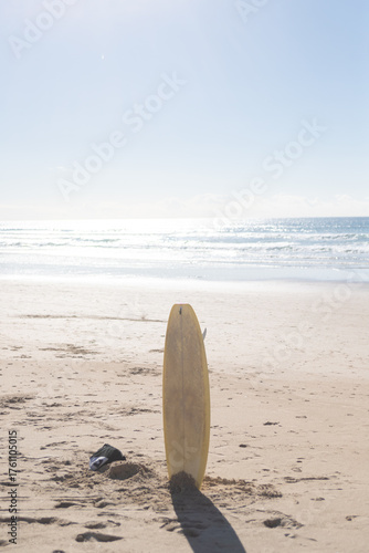 Canvas Print Yellow surfboard standing in sand on Atlantic beach