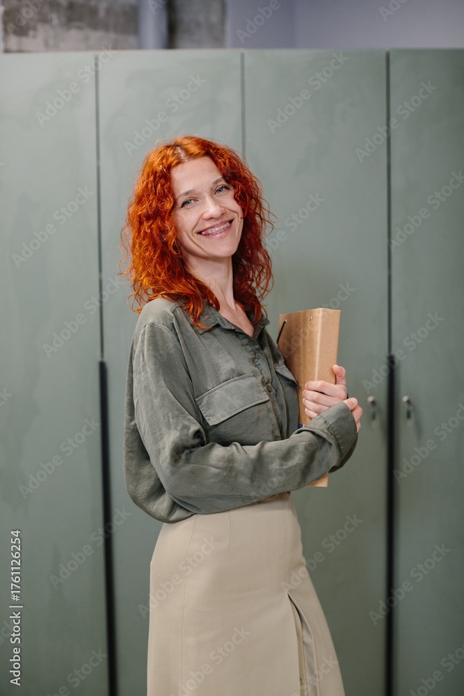 Fototapeta premium Smiling businesswoman holding documents standing in an office