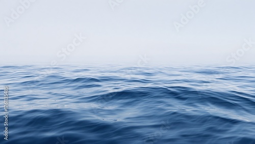 Calm blue ocean waves under a soft hazy sky creating a serene seascape