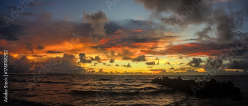 Panoramic view of the coast at sunset with orange and reddish clouds over the sea.