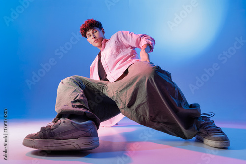 Billede på lærred Hip hop dancer in baggy pants and sneakers strikes a low-angle pose, urban style for music, sport, fashion and event promotions