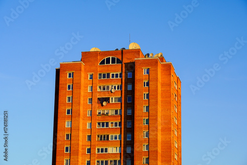 Brick apartment building under clear blue sky during golden hour in urban setting