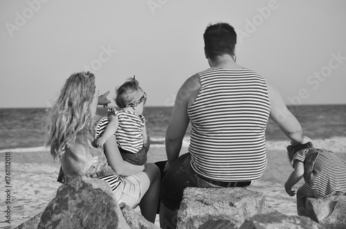 Family sitting on seashore looking at waves meditating beach summer red poses people 3 