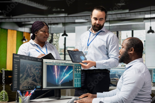 Team of sustainable energy tech company technicians monitoring eco power line towers. Teamworking colleagues use CAD software on PC to upgrade transmission tower systems, reducing carbon emissions