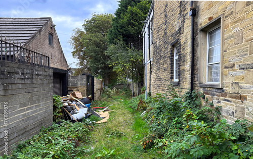 Between two worn facades, a Victorian alley sprawls, overgrown, unruly, and littered with the detritus of a city once forged in steel, A hush hangs heavy in the weeds in post industrial Bradford, UK