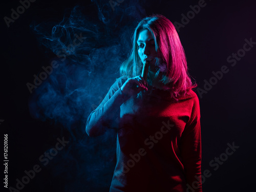 Woman vaper in dark room. W...