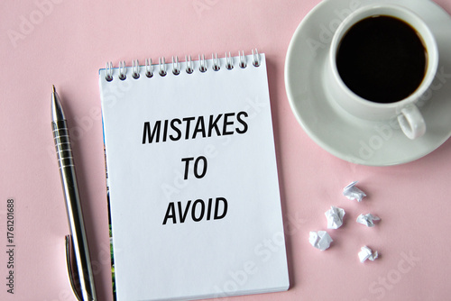 MISTAKES TO AVOID - words in a notebook on a pink background with a cup of coffee
