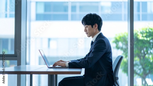 オフィスでノートパソコンで真剣に仕事をする若い日本人男性 16:9サイズ AI生成素材