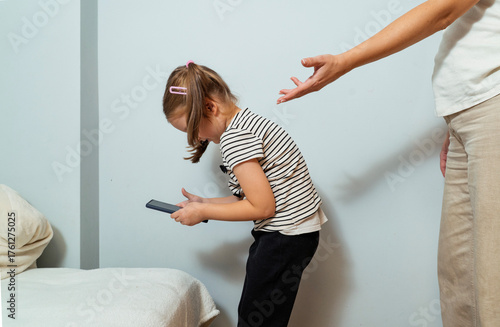 Too much screen time concept, mother asking her little daughter to return her smartphone 