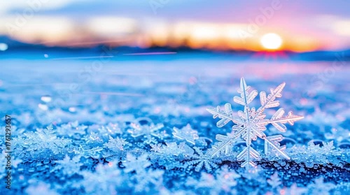 Macro snowflake and ice crystals on frozen surface with blurred warm winter sunrise background