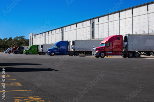 Obraz na plátne Logistics warehouse exterior with loading bays and trucks.