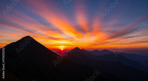 Dramatic sunrise over mountain range, with vibrant colors painting the sky and creating a stunning and aweinspiring natural spectacle