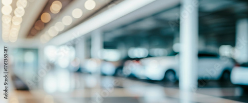 Blurred interior view of a modern showroom or parking area with vehicles under soft lighting, polished floors, and wide glass walls that reflect colors of elegant cars in a peaceful contemporary.